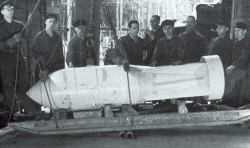 Produktion im Zweiten Weltkrieg: Mitarbeiter posieren beim Verladen einer Fliegerbombe 