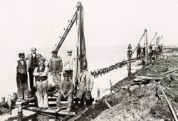 Eine Gruppe von Arbeitern posiert auf ihren Rammen für ein Bild vom Dammbau